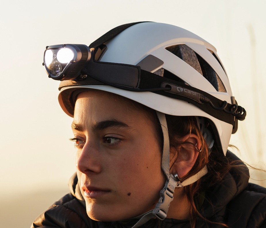 A production headlamp mounted on a cycling helmet at dusk